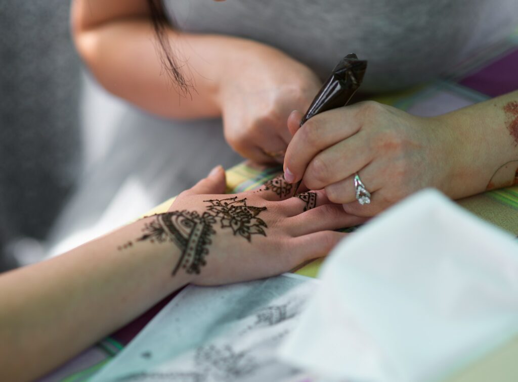 Artist applying henna tattoo on women hands